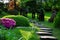 Stony path decorated with bonsais in blooming garden with permeating sunlight