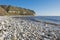 Stony pebble beach with cliffs in costal landscape scene