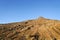 Stony pinnacle with scrubby vegetation under blue sky