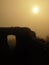 The stony ruin of medieval stronghold tower on hill. Early morning sunshine hidden in heavy mist.