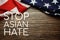 Stop Asian Hate text with USA flag on wooden background