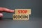 Stop ecocide symbol. Wooden blocks with words stop ecocide. Businessman hand. Beautiful grey background, copy space. Business,