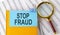 STOP FRAUD text on sticker on notebook with magnifier and chart. Business