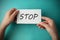 Stop inscription. Woman holding paper with STOP lettering in hands isolated on blue background