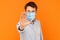 Stop! keep your distance. Portrait of angry or aggressive young worker man with surgical medical mask standing with stop hand and