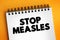 Stop Measles - get the measles, mumps, and rubella MMR vaccine, text concept on notepad