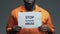 Stop physical abuse phrase on cardboard in hands of black prisoner, assault