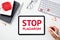 STOP PLAGIARISM message on tablet screen, keyboard, glasses, notebooks on white office desk table top view