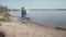 Stop pollution, cute boy pulls heavy bag of trash on pointing sign on river beach after cleaning up plastic garbage and