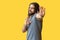 Stop. Portrait of scared or confused bearded young man with long curly hair in grey tshirt standing with stop hand sign gesture