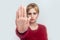 Stop! Portrait of serious or anger beautiful young blond woman in red blouse standing with stop gesture sign and looking at camera