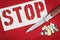 A stop sign, the knife and pills on red background. The risk of crime