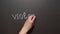 Stop Violence. A left female hand writes the word by chalk on a black board