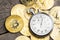 Stopwatch and bitcoin. Gold coins of cryptocurrency and a clock on a wooden table