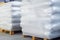 Storage of packaged goods or cargo in warehouse. On wooden pallets there are bags of cement wrapped with polyethylene