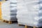 Storage of packaged goods or cargo in warehouse. On wooden pallets there are bags of cement wrapped with polyethylene