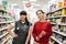 Store employees, the Director and Manager, pose against the background of food shelves, in the aisle. Two beautyful young