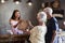 Store Owner Standing Behind Cash Desk Serving Senior Customers