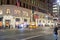 Storefront Christmas Decoration with Bright Lights at Night in Manhattan, New York City. A Taxi is About to Cross the Crossroad.