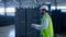 Storehouse employee making notes calculating blue boxes wearing green uniform