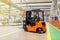 Storehouse employee in uniform working on forklift in modern automatic warehouse. Boxes are on the shelves of the