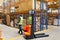 Storehouse employee in uniform working on forklift in modern automatic warehouse. Boxes are on the shelves of the warehouse.
