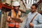 Storehouse factory worker discussing document with list of goods with warehouse manager holding clipboard writing using