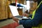 Storehouse worker checking stock and inventory on laptop while sitting in retail warehouse