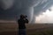 storm chaser, with camera in hand, capturing up-close shots of tornado touching down