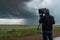 storm chaser in fierce storm, recording wind speeds and atmospheric pressure