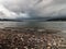 Storm clouds building over rocky pebble covered shore