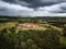 Storm clouds loom over abandoned mansion in rural setting