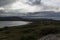 Storm clouds over the green valley and the lake, highlands.