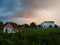 Storm cumulonimbus cloud with heavy rain or summer shower, severe weather and sun glow behind rain. Cityscape with abandoned house