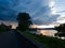 Storm cumulonimbus dark cloud with heavy rain or summer shower, severe weather. Landscape with Sava river and promenade in