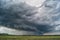 Storm cyclone over summer fields, hills and forests