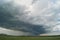 Storm cyclone over summer fields, hills and forests