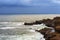 Storm darkening skies along rocky coastal shores