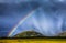 Storm rain shower cloud colourful bright vibrant rainbow over rural landscape Great Britain United Kingdom