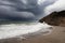 Stormy coastline with water splash and dark sky, sandy beach with turquoise sea, Sitges, Spain