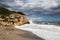 Stormy coastline with water splash and dark sky, sandy beach with turquoise sea, Sitges, Spain