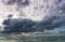 Stormy dark clouds above the sea with sandy beach and curling waves