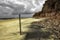 Stormy day at the beach A human figure moves away on the horizon. Wooden post nailed to the sand. Desolate beach