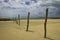 Stormy day at the beach A human figure moves away on the horizon. Wooden post nailed to the sand. Desolate beach