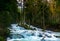 A stormy mountain river flows among huge stones in the forest slopes of the Caucasus Mountains