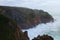 Stormy ocean with waves braking on the cliffs. Overcast weather, stormy wind. Scenic morning foggy landscape. Atlantic ocean