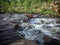 A stormy river flows through a green valley.