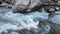 Stormy running stream of water in a mountain river. Autumn, spring, winter season. Frozen icicles on the rocks