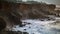 Stormy sea washing rocky coastline on dull day. Foaming waves hitting wild shore