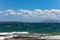 Stormy sea, waves splashing on rocks, blue sky with clouds background